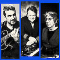 Das Bild zeigt drei Musiker in Schwarz-Weiß-Aufnahmen mit Halbtoneffekt, die vor einem blauen Hintergrund präsentiert werden. Links spielt eine Person Gitarre, in der Mitte sitzt jemand am Keyboard oder Piano, und rechts ist eine Person mit Brille an einem weiteren Instrument zu sehen.