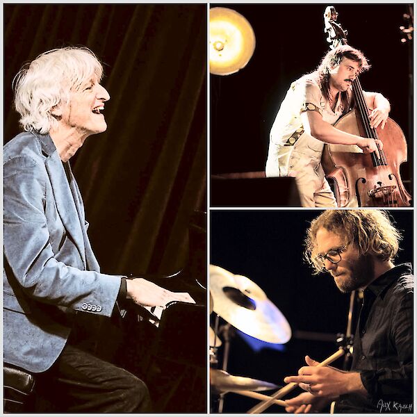 Das Bild zeigt eine Collage von drei Jazzmusikern während einer Live-Performance: links ein grauhaaariger Pianist in blauem Sakko am Klavier, rechts oben ein Bassist mit Kontrabass und rechts unten ein Schlagzeuger am Drumset. Alle drei Musiker sind konzentriert beim Spielen zu sehen und werden von warmem Bühnenlicht beleuchtet.